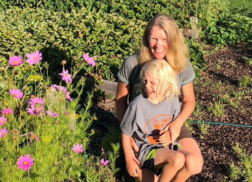 Megan Schuknecht and a child pose for photo in a flower garden